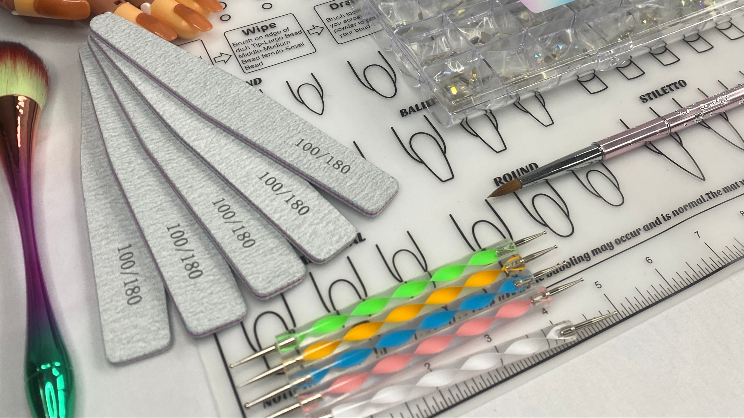 Nail art tools and supplies including a lamp, nail polish bottles, and a clear acrylic block on a white surface.